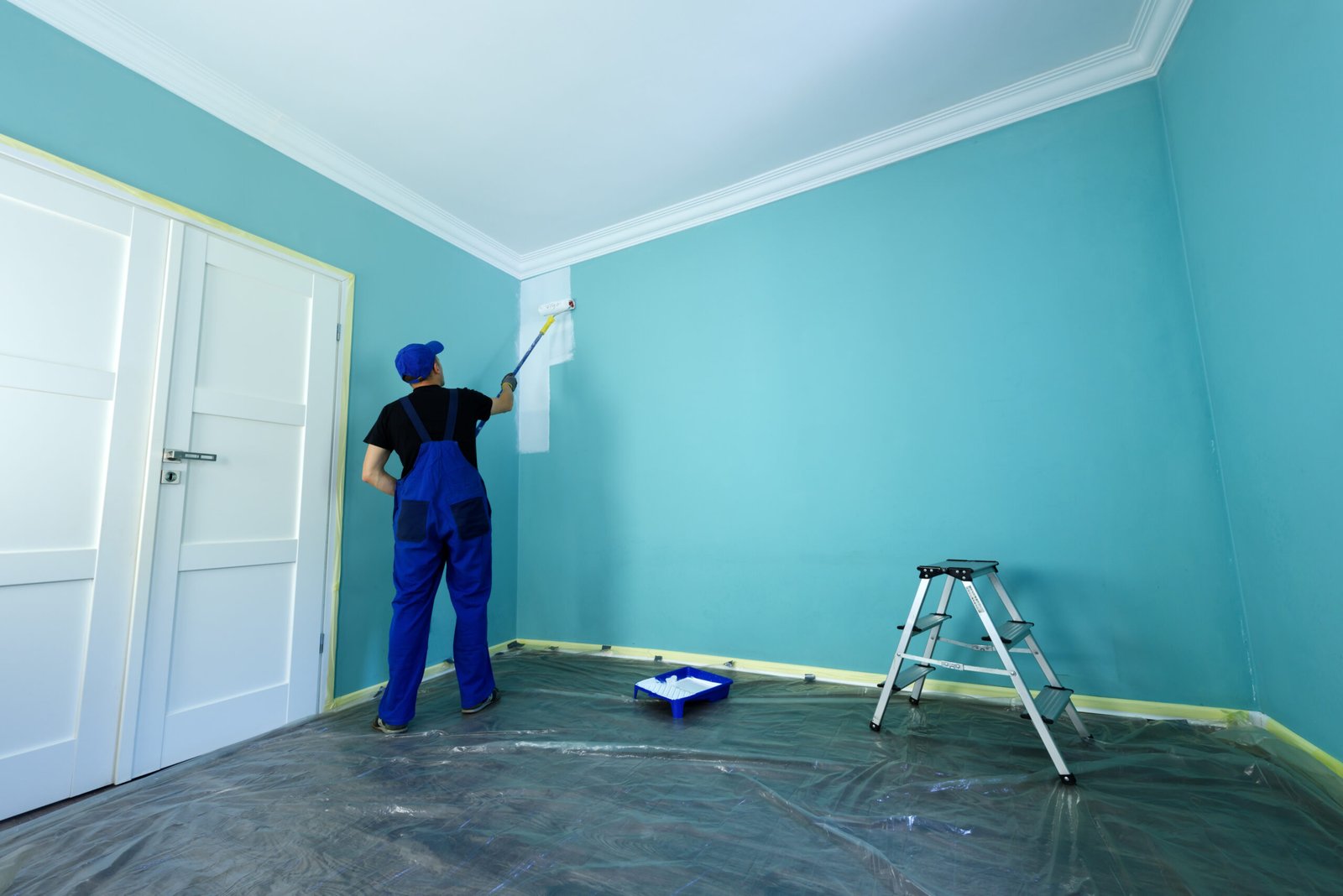 Painter applying paint to an interior wall with a roller